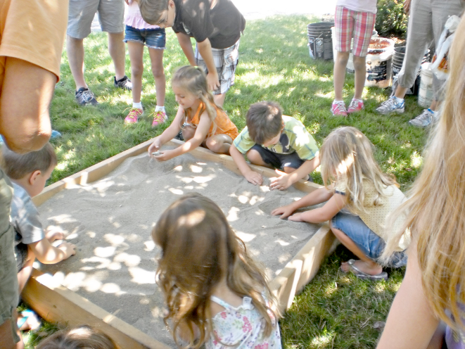 [photo of young children playing in a sandbox]