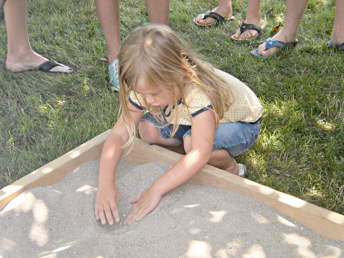 [photo of a young girl playing in a sandbox]